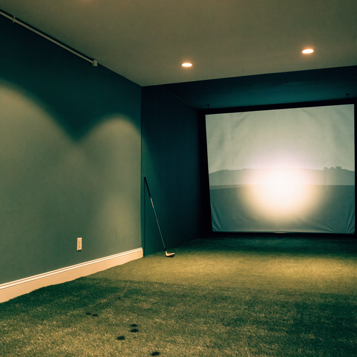 Finished home golf simulator room with impact screen and turf hitting mat