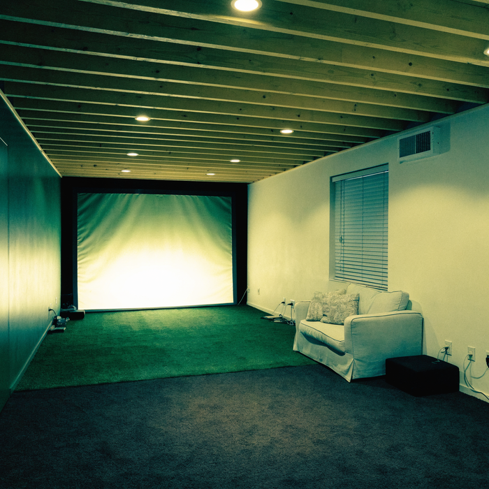 Finished basement golf simulator room with low ceiling and exposed painted joists