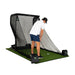 Person practicing golf swings on a netted hitting mat with a white background