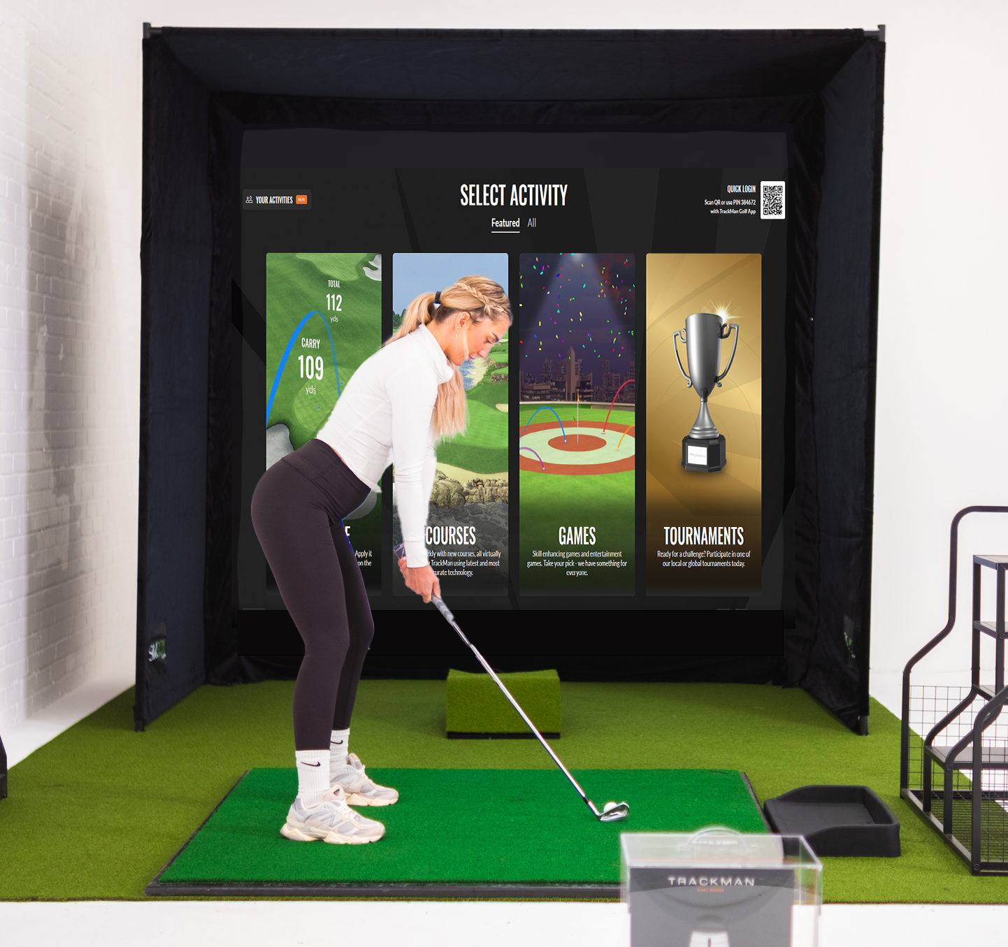 Person using a golf simulator with a screen displaying various activities.